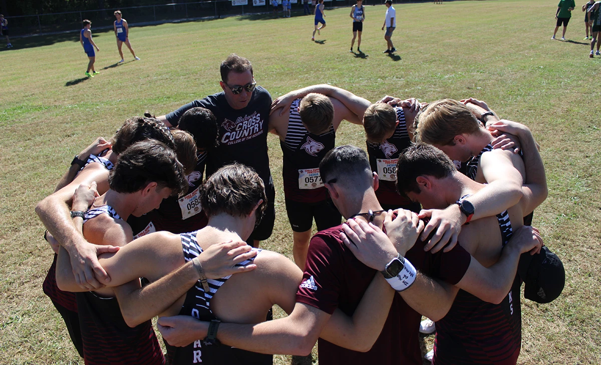 Cross Country Coach praying with the team